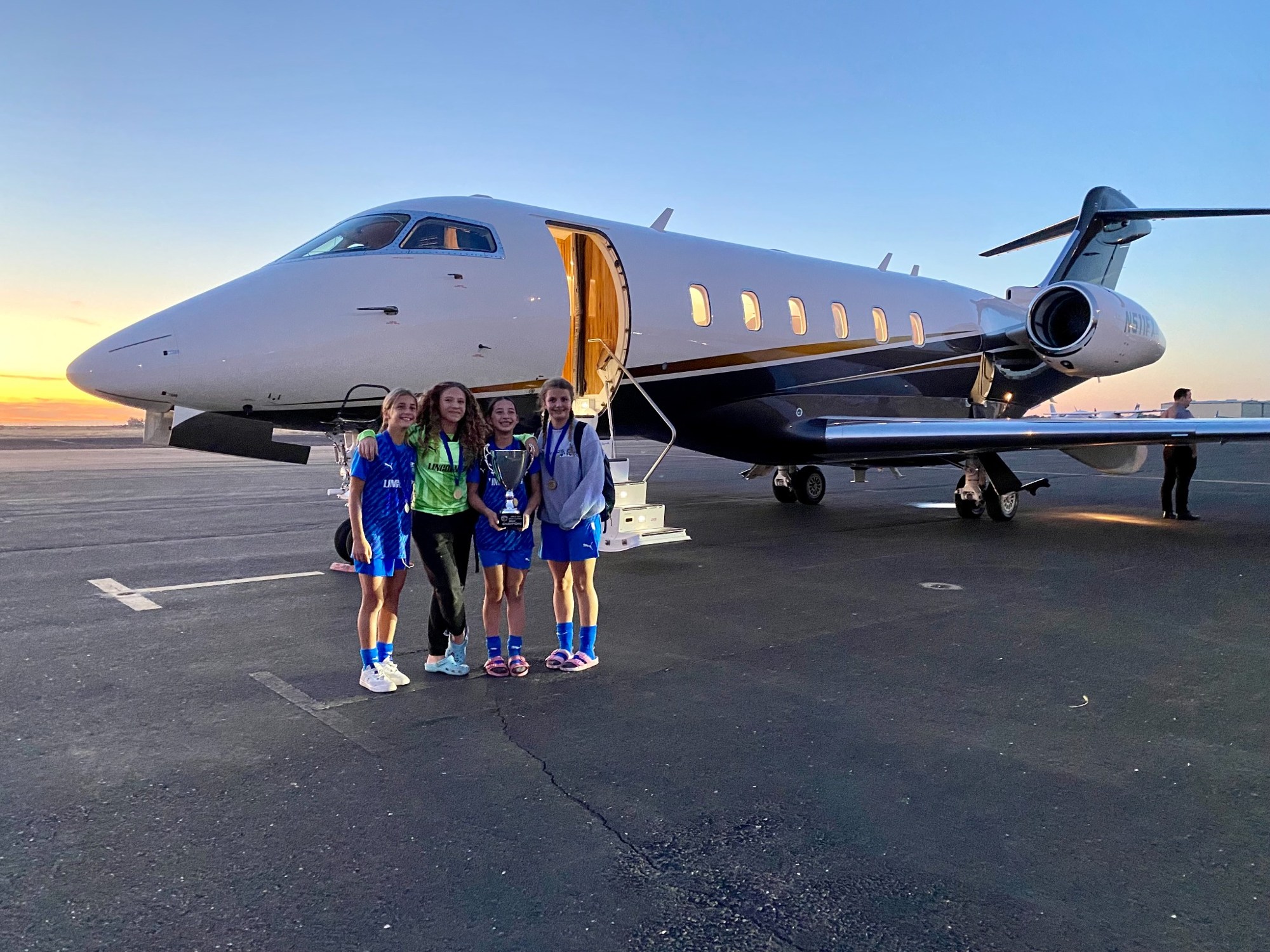 Teammates beside a jet at sunset